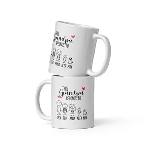 Puede incluir: Taza de cer&aacute;mica blanca con un dise&ntilde;o en negro y rojo. La taza dice "This Grandpa Belongs To" con una familia de figuras de palo y los nombres "Jack, Ted, Anna, Alex, Max".