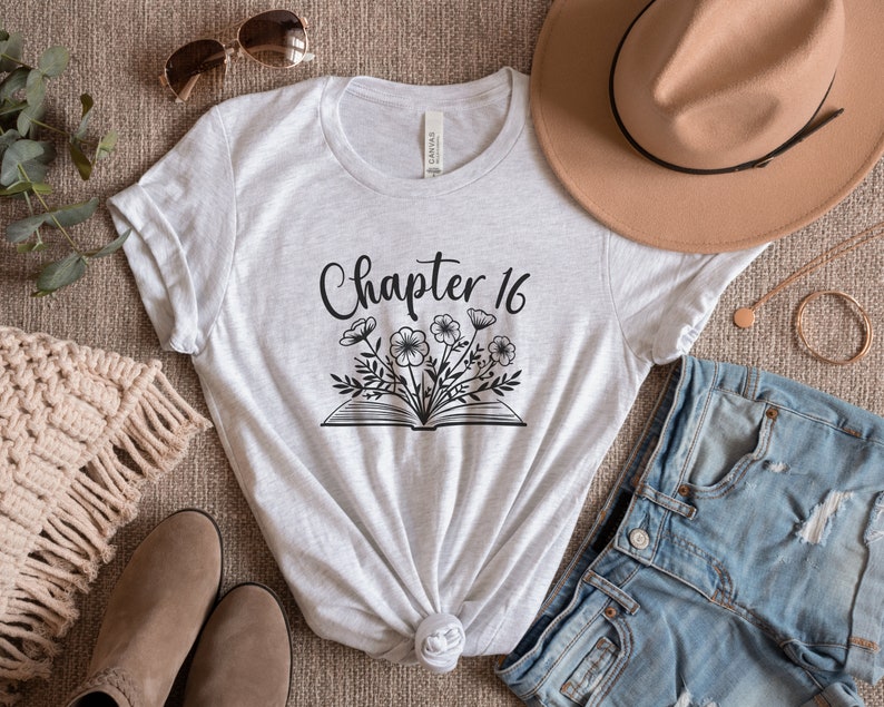 May include: A gray t-shirt with the text "Chapter 16" and a black and white illustration of a book with flowers.