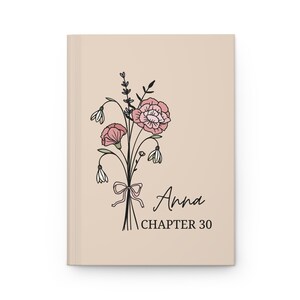 May include: A beige journal featuring a floral illustration of pink and white flowers with a black outline. The text "Anna Chapter 30" is printed below the illustration.