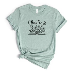 May include: A light green t-shirt with a black graphic of a book with flowers growing out of it and the text "Chapter 16".