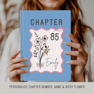May include: A light blue book with the word "CHAPTER" at the top. The cover features a floral design with the number "85" and the name "Emily". The text at the bottom reads: PERSONALIZE CHAPTER NUMBER, NAME & BIRTH FLOWER.