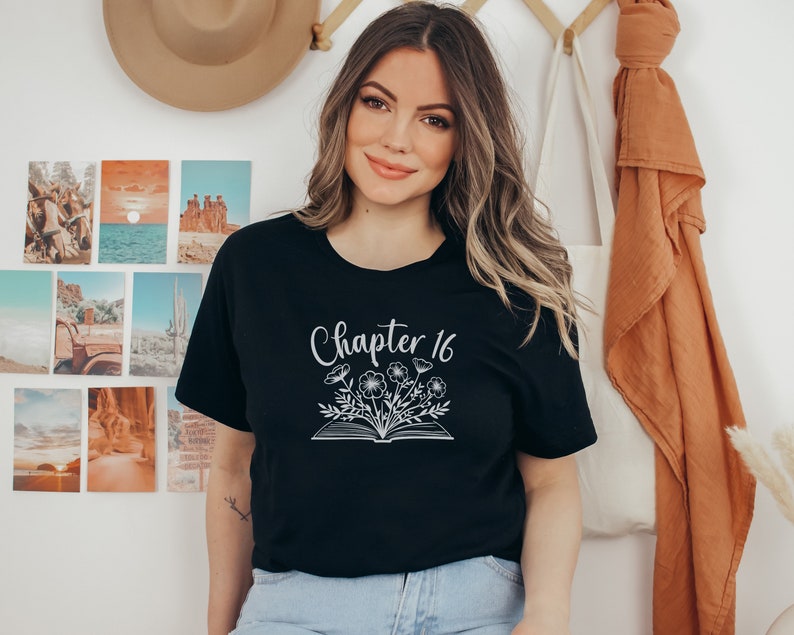 May include: Black t-shirt with white text that says "Chapter 16" and a graphic of a book with flowers coming out of it.