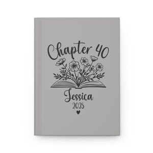 May include: Gray journal cover with a black and white illustration of an open book with flowers coming out of it. The text "Chapter 40" is above the book and the text "Jessica 2025" is below the book.