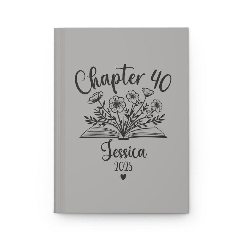 May include: Gray journal cover with a black and white illustration of an open book with flowers coming out of it. The text "Chapter 40" is above the book and the text "Jessica 2025" is below the book.