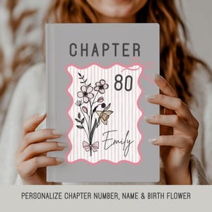 May include: A grey book with the word "CHAPTER" at the top. The cover features a pink-bordered design with the number "80", floral illustrations, and the name "Emily". The design includes a bow and vertical stripes.