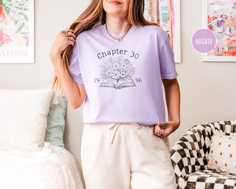 May include: A light purple t-shirt with the text "Chapter 30" above a floral design and the numbers "1996". The shirt is a soft, comfortable material.