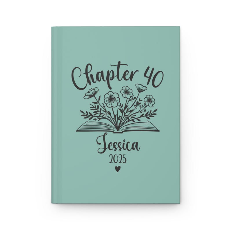 May include: A teal blue journal cover with a black illustration of an open book with flowers growing out of it. The text "Chapter 40" is above the book and the text "Jessica 2025" is below the book.