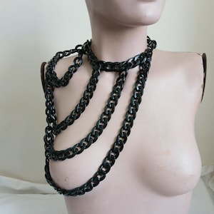 May include: A black chain necklace with multiple layers. The chain is thick and has a curb link design.