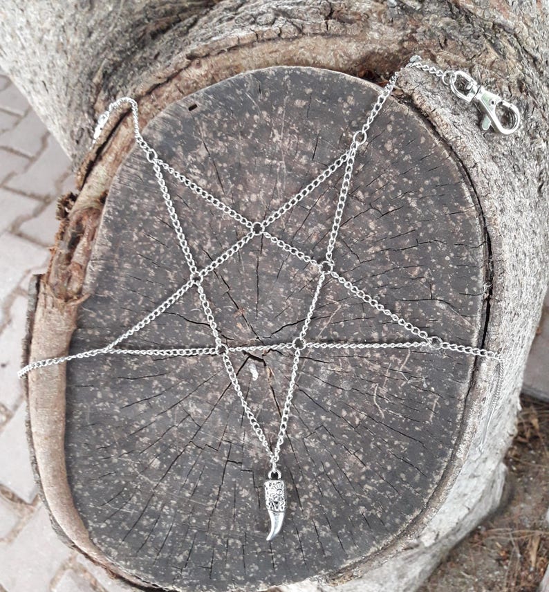 May include: A silver chain body harness with a pentagram design and a silver horn pendant.