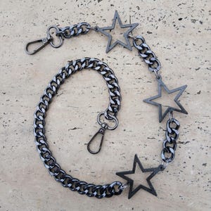 May include: A black chain with three star-shaped charms. The chain has a lobster clasp on one end and a swivel clasp on the other.