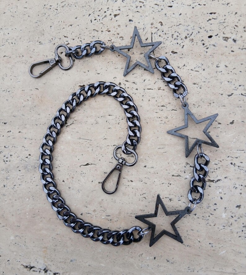 May include: A black chain with three star-shaped charms. The chain has a lobster clasp on one end and a swivel clasp on the other.