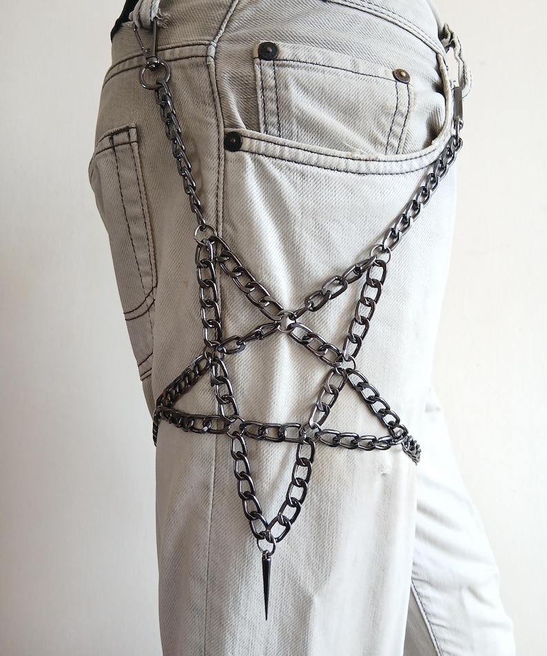 Puede incluir: Un accesorio de cadena plateada con un dise&ntilde;o de estrella de cinco puntas. La cadena est&aacute; sujeta a una trabilla y cuelga por la pierna, con una punta en la parte inferior de la estrella. El accesorio se lleva sobre unos vaqueros claros.