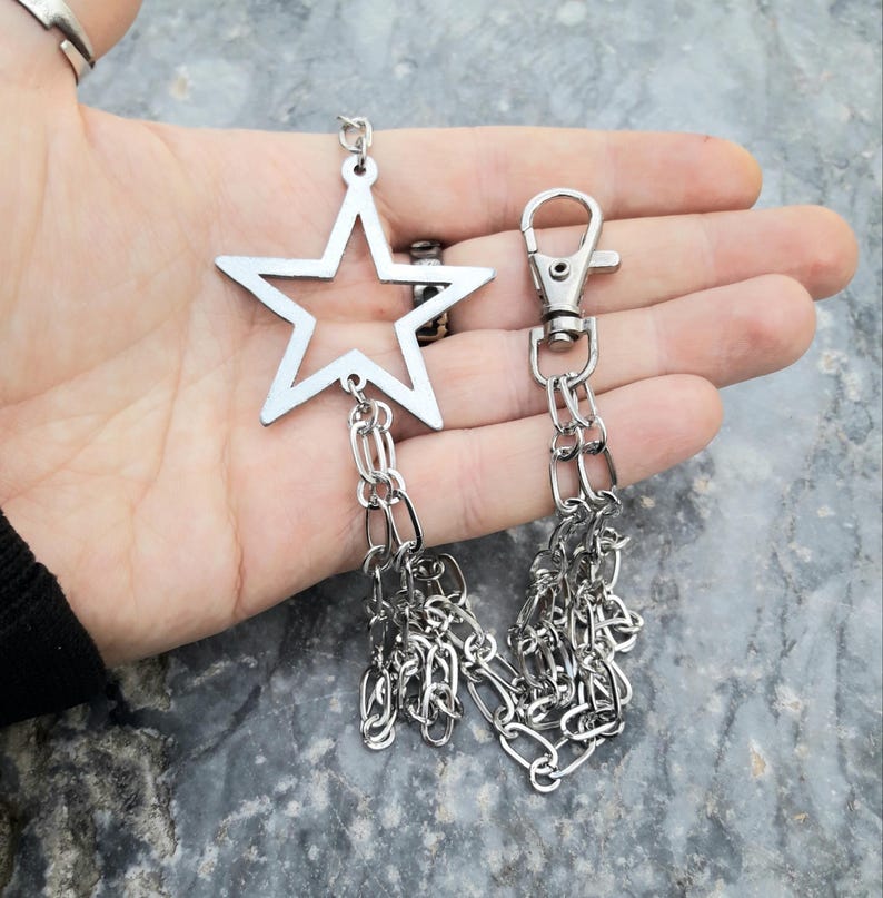 May include: A silver star-shaped keychain with a double chain attached to a silver lobster clasp.
