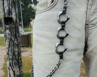 May include: A silver-toned metal chain with three decorative rings and black leather accents, attached to a pair of light-colored jeans. The chain is a stylish accessory.