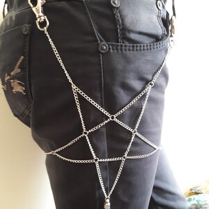 May include: A silver chain body harness with a star-shaped design. The chain is attached to a clip that can be worn on a belt loop.