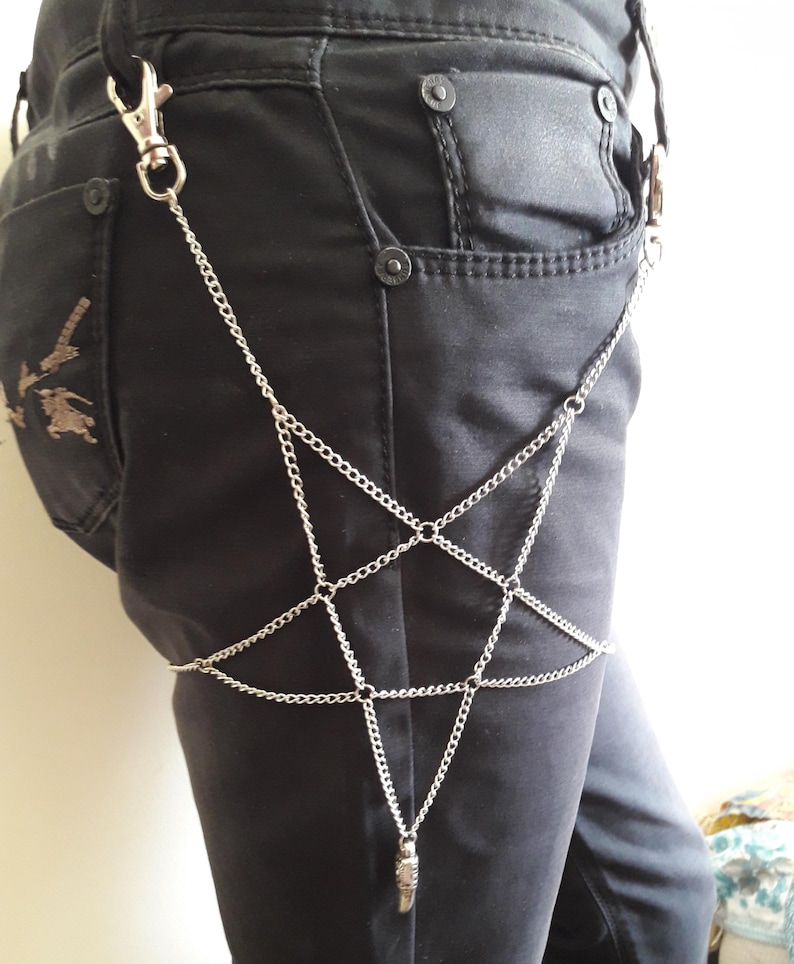 May include: A silver chain body harness with a star-shaped design. The chain is attached to a clip that can be worn on a belt loop.