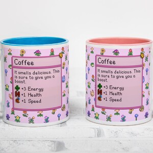 May include: Two white ceramic coffee mugs with a pink and floral design. One mug has a blue handle and interior, the other has a pink handle and interior. Each mug has the word "Coffee" and game-like stats.