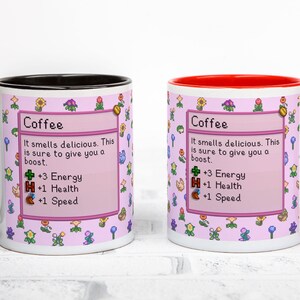 May include: Two white ceramic coffee mugs with a pink floral design and the word "Coffee" in a box. One mug has a black handle and rim, the other has a red handle and rim. The text on the mugs says "It smells delicious. This is sure to give you a boost."