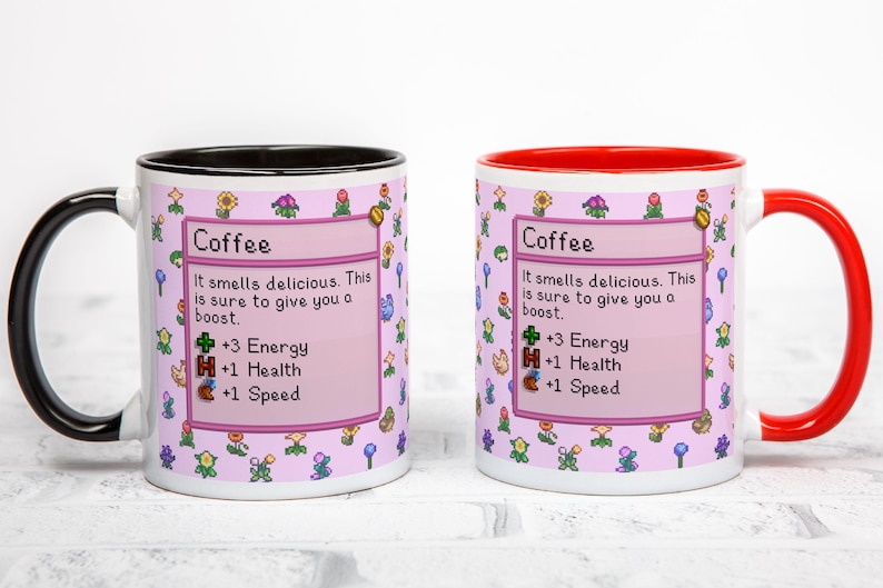 May include: Two white ceramic coffee mugs with a pink floral design and the word "Coffee" in a box. One mug has a black handle and rim, the other has a red handle and rim. The text on the mugs says "It smells delicious. This is sure to give you a boost."