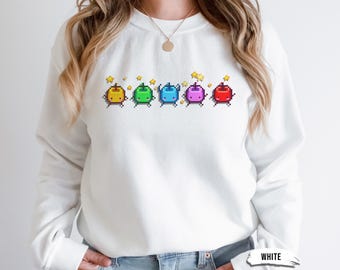 May include: White sweatshirt featuring a rainbow pixelated apple design. The apples are flying with stars around them.