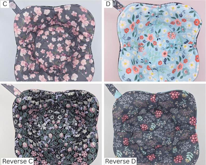 May include: Four quilted bowl cozies with floral patterns. One has a gray background with pink flowers, another has a light blue background with red and orange flowers, and the other two have dark backgrounds with floral designs. Each cozy has a loop for hanging.