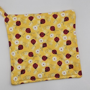 May include: Yellow quilted hot pad with a ladybug print. The hot pad has a loop for hanging.