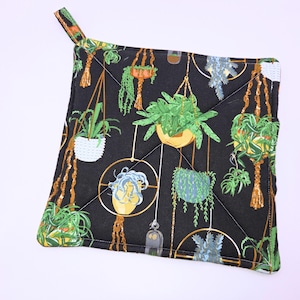 May include: Black quilted hot pad with a pattern of hanging plants in various shades of green, yellow, and brown. The plants are in white, yellow, and blue pots.