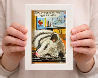 Lámina artística de una zarigüeya divertida: «Deja de fingir y ponte a trabajar» en marco blanco