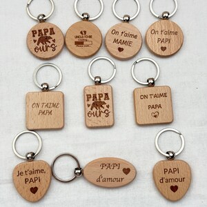 Peut inclure: Plusieurs porte-clés en bois avec des anneaux argentés. Les porte-clés ont différentes formes, rondes, rectangulaires et en forme de cœur. Chaque porte-clés est gravé de textes tels que "PAPA ours", "On t'aime PAPI" et "Je t'aime, PAPI".
