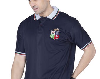 May include: Navy blue polo shirt with a white collar and red and green stripes. The shirt features a crest on the left chest. The sleeves have matching red and green stripes. The shirt is paired with blue jeans.