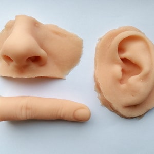 May include: Three realistic-looking silicone body parts: a nose, an ear, and a finger. The parts are flesh-coloured and appear to be made of soft, flexible material.