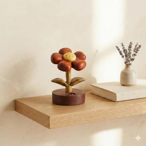 May include: A wooden flower sculpture with a dark brown base, stem, and petals. The flower's center is a light yellow color. The sculpture sits on a wooden shelf. A small vase with lavender and a book are also on the shelf.