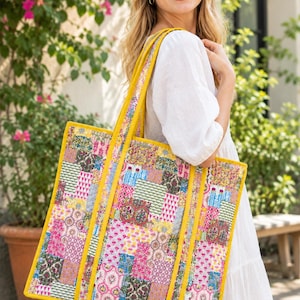 May include: A large rectangular tote bag featuring a patchwork design of various floral and geometric patterns in shades of pink, yellow, green, and blue, finished with solid mustard yellow fabric trim and two matching shoulder straps.