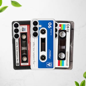 Puede incluir: Tres fundas para smartphone con diseños de casetes retro. La funda de la izquierda es negra con detalles rojos y el texto "my custom mix tape". La central es blanca y azul con "my custom mix tape" y "90". La de la derecha es blanca con "FE 90".