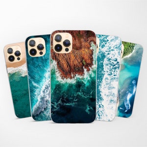 May include: Five different phone cases with ocean-themed designs. The cases feature images of waves crashing on the shore, rocky coastlines, and aerial views of the ocean.