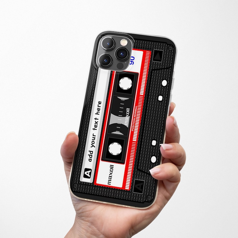 May include: A black iPhone case with a red and white cassette tape design. The case has a clear back and a black frame. The cassette tape design features the text "maxoll" and "add your text here".