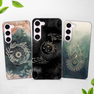 May include: Three phone cases with a celestial theme. The cases feature a black background with gold accents and illustrations of the sun, moon, and stars. The cases are made of clear plastic and have a matte finish.