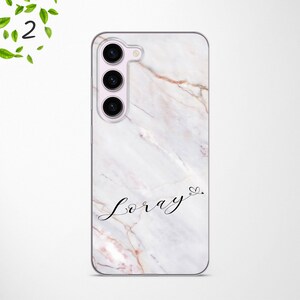May include: A white marble phone case with a black inscription that reads "Loray" with a small heart symbol.