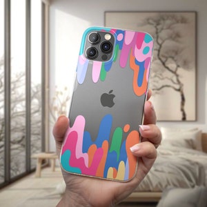 Pode incluir: Uma capa transparente para telefone com um design abstrato colorido de tinta pingando em tons de rosa, azul, verde, laranja e amarelo. A capa é projetada para um iPhone.