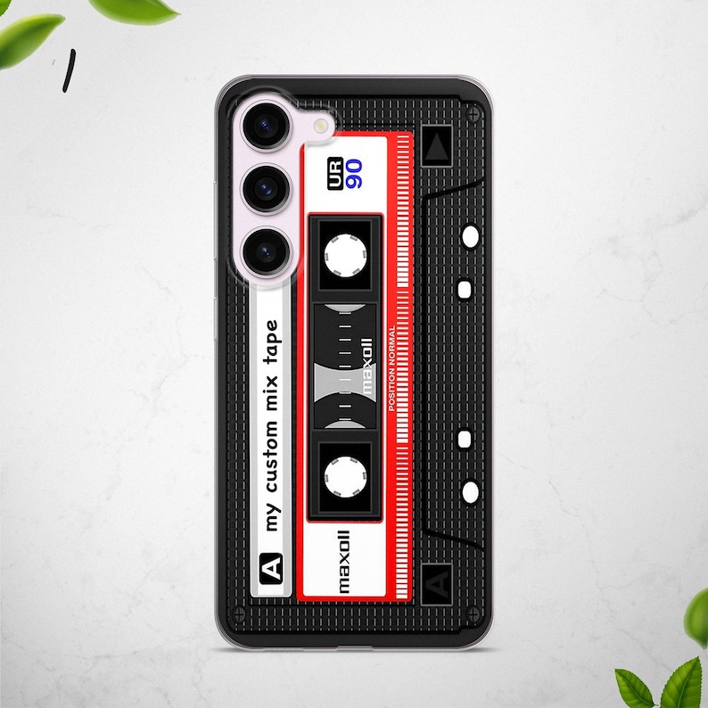 May include: A black phone case with a retro cassette tape design. The case features a red and white cassette tape with the text "UR 90", "maxoll", and "my custom mix tape".