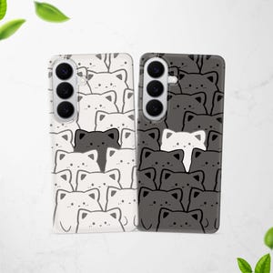 May include: Two rectangular smartphone cases featuring a repeating pattern of stylized cat faces. The left case is white with black outlines and one black cat, while the right case is dark gray with black outlines and one white cat, both with camera cutouts.