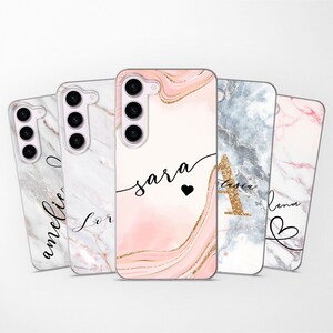 May include: Four different phone cases with marble patterns and personalized names. The cases are pink, white, gray, and light pink with gold accents. The names on the cases are Amelia, Lor, Sara, and Lena.
