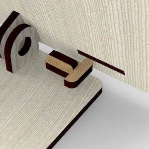 May include: A close-up of a wooden cabinet door with a mortise and tenon joint. The cabinet door is light-colored with a wood grain pattern. The joint is dark brown and appears to be a decorative element.