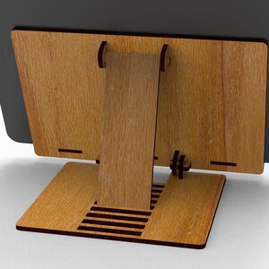 May include: A wooden tablet stand with a natural wood grain finish. The stand has a rectangular base, a vertical support, and a back panel to hold the tablet. The design features slots and cutouts for stability and cable management.