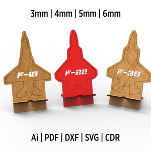 Puede incluir: Tres soportes de teléfono de madera con forma de aviones de combate. Los soportes están disponibles en tres tamaños: 3 mm, 4 mm y 5 mm. Los soportes están etiquetados con el texto "F-163", "F-2222" y "F-3355".