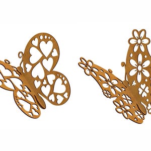 Pu&ograve; includere: Due ritagli di farfalle in legno. Una farfalla presenta ritagli a forma di cuore, mentre l'altra ha ritagli a forma di fiore. Entrambe le farfalle sono di colore marrone caldo e sono su uno sfondo bianco.