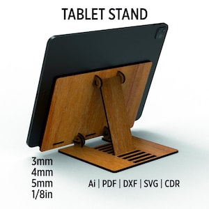 Può includere: Un supporto per tablet in legno con un tablet nero in posizione. Il supporto è realizzato in legno marrone chiaro e ha una gamba di supporto. Il testo "TABLET STAND" è in alto. Il supporto è progettato per tablet di 3 mm di spessore.