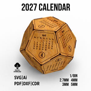 May include: A wooden icosahedron-shaped 2027 calendar with pentagonal faces. Each face displays a month, days of the week, and a circled number. Text includes 2027 CALENDAR, DIGITAL DOWNLOAD, SVG, Ai, PDF, DXF, CDR, and measurements 1/8IN, 2.7MM, 4MM, 3MM, 5MM.