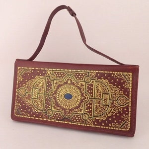 Bolso de mano o de noche de piel florentina de los años 60, de piel burdeos con estampado dorado metalizado. Accesorios vintage. Por Vogini Venecia, Italia