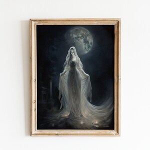 Puede incluir: Una pintura enmarcada de una mujer con un vestido blanco de pie en un cementerio por la noche. La mujer está rodeada de velas y una luna llena está en el fondo.